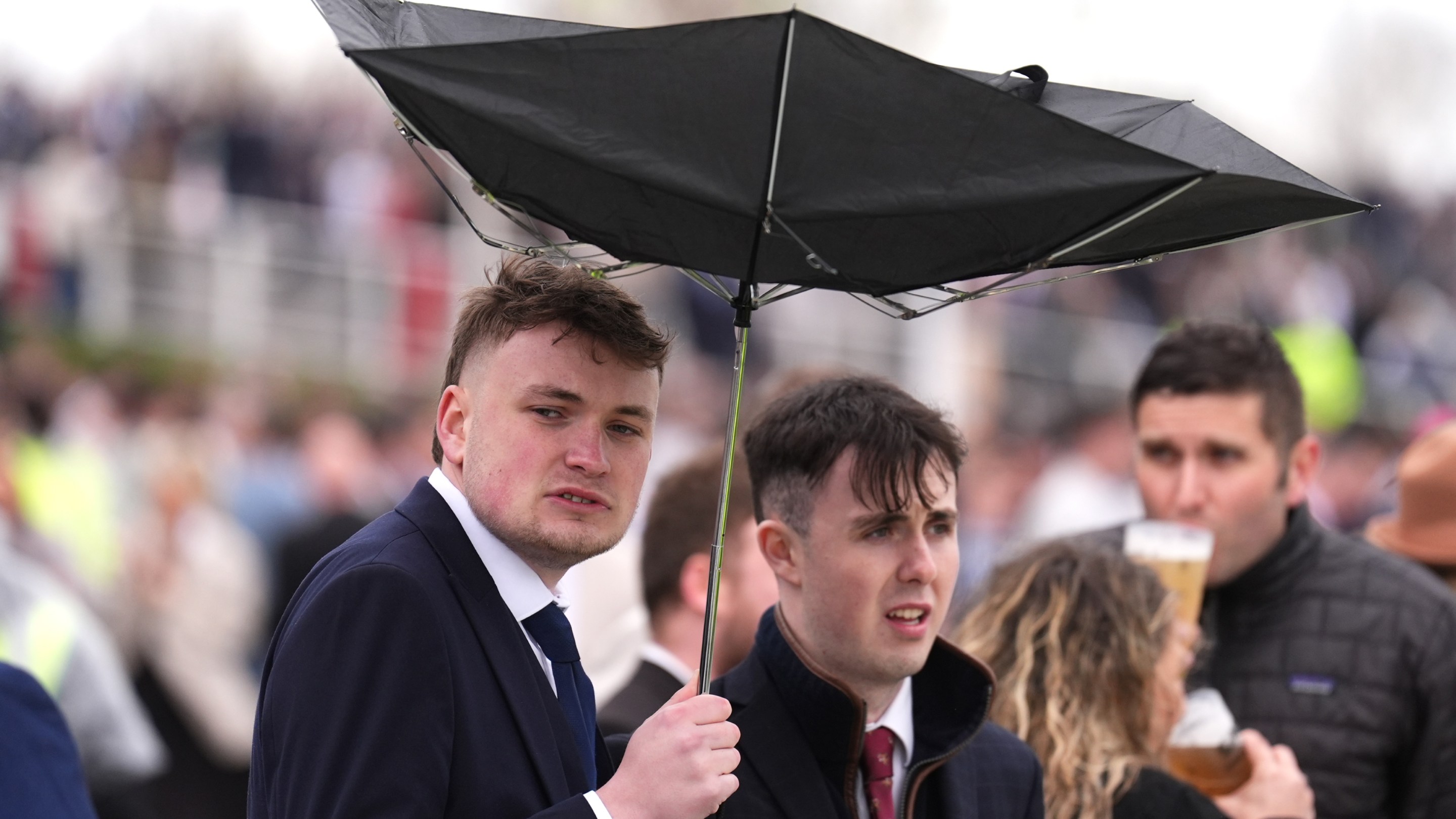 A racegoer holds an umbrella which is inside out on Grand National Day of the Randox Grand National Festival 2026 at Aintree Racecourse.