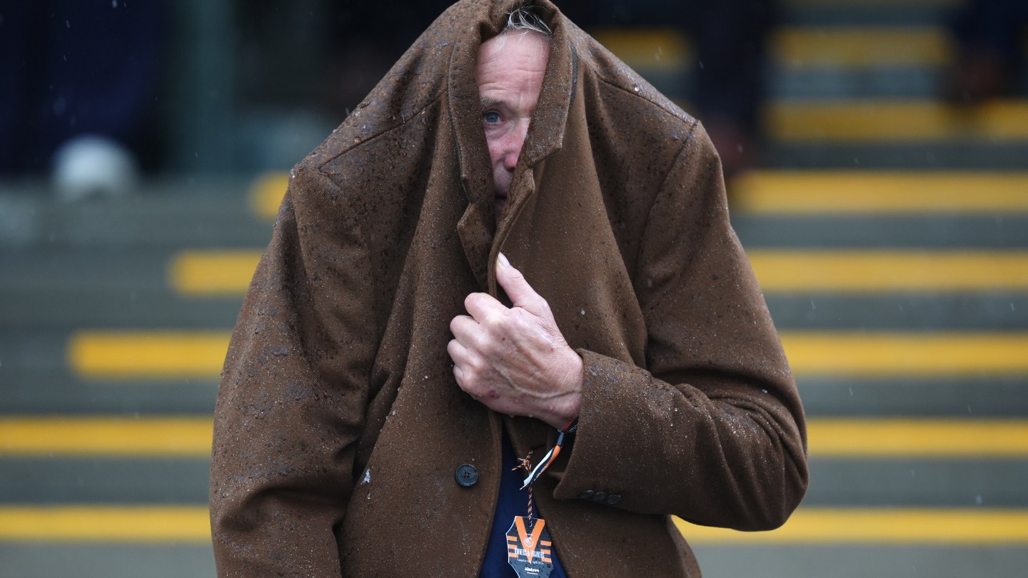 Racegoers attempts to protect themselves from the rain as they watch the Turners Mersey Novices' Hurdle on Grand National Day.