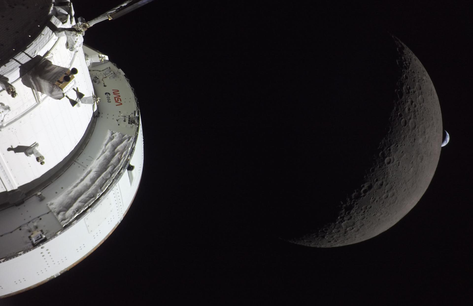 The Earth sets over the Moon, with Orion in the foreground.