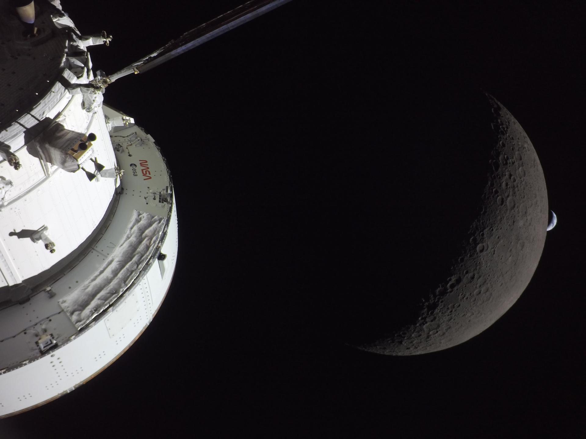 The Earth sets over the Moon, with Orion in the foreground.