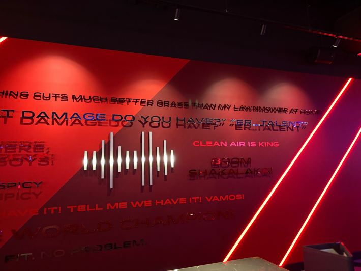 The quote wall of the F1 Arcade, including "CLEAN AIR IS KING" and "VAMOS."