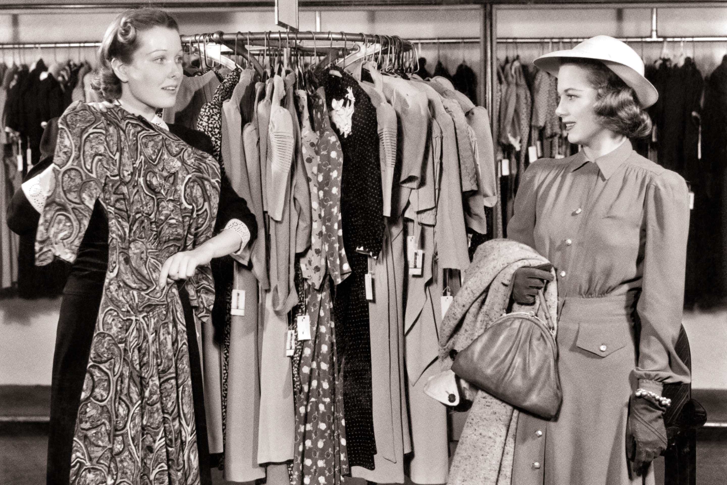1940s Helpful Department Store Saleswoman Holding A Dress For Ctomer Wearing A Hat With Coat And Handbag Over Her Arm