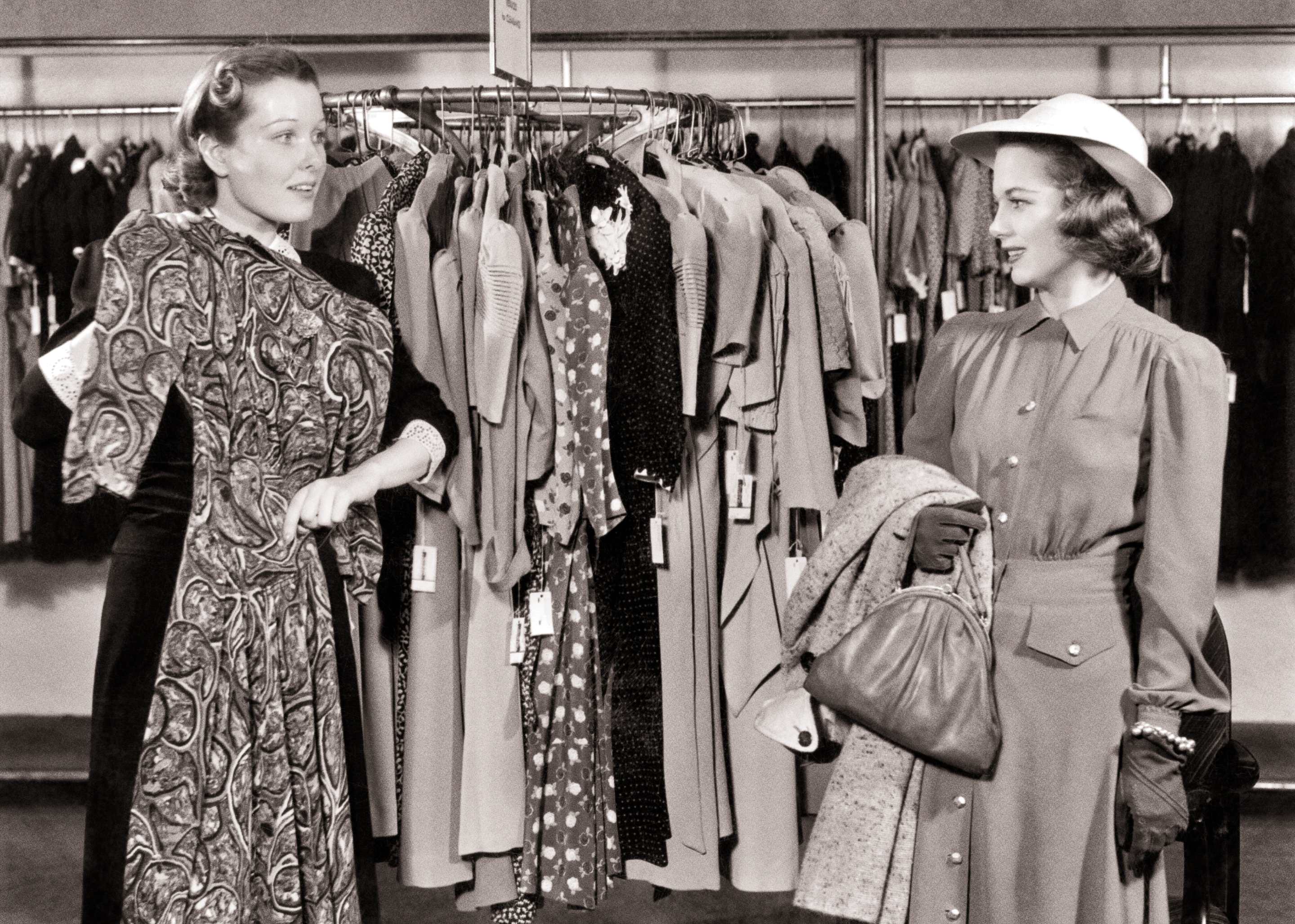 1940s Helpful Department Store Saleswoman Holding A Dress For Ctomer Wearing A Hat With Coat And Handbag Over Her Arm