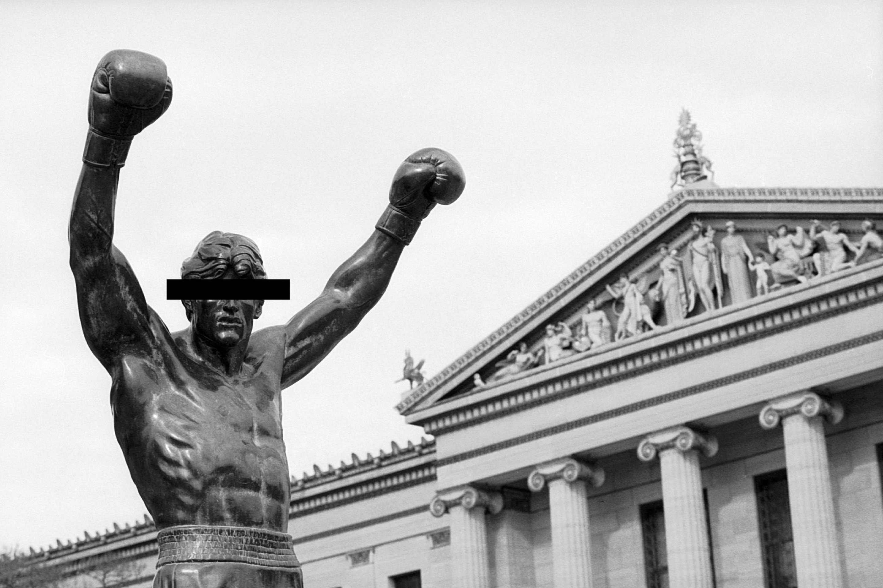 PHILADELPHIA, PENNSYLVANIA - CIRCA 1990: The Rocky statue stands atop the Philadelphia Museum of Art steps in Philadelphia, Pennsylvania in 1990. The statue of fictional character Rocky Balboa, as portrayed by actor Sylvester Stallone, was created for and used in the Rocky III movie. It was later located outside the Spectrum at the South Philadelphia Sports Complex. In 1990, it was temporarily moved to the top of the museum steps, which feature prominently in the original Rocky film, for the filming of Rocky V. In 2006, the statue was moved to a grassy area at street level on museum grounds. (Photo by James Drake/Getty Images)