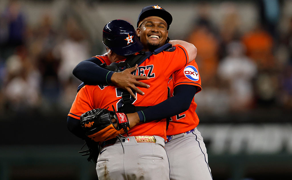 alimber santos smiles big over the shoulder of the catcher he is hugging.