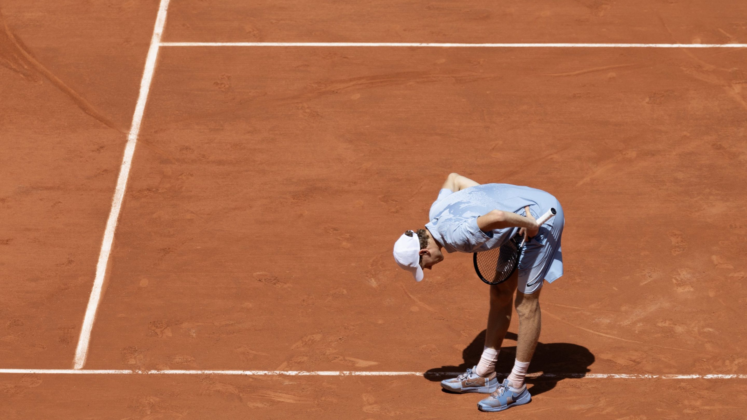 Jannik Sinner bent over in pain during his French Open match
