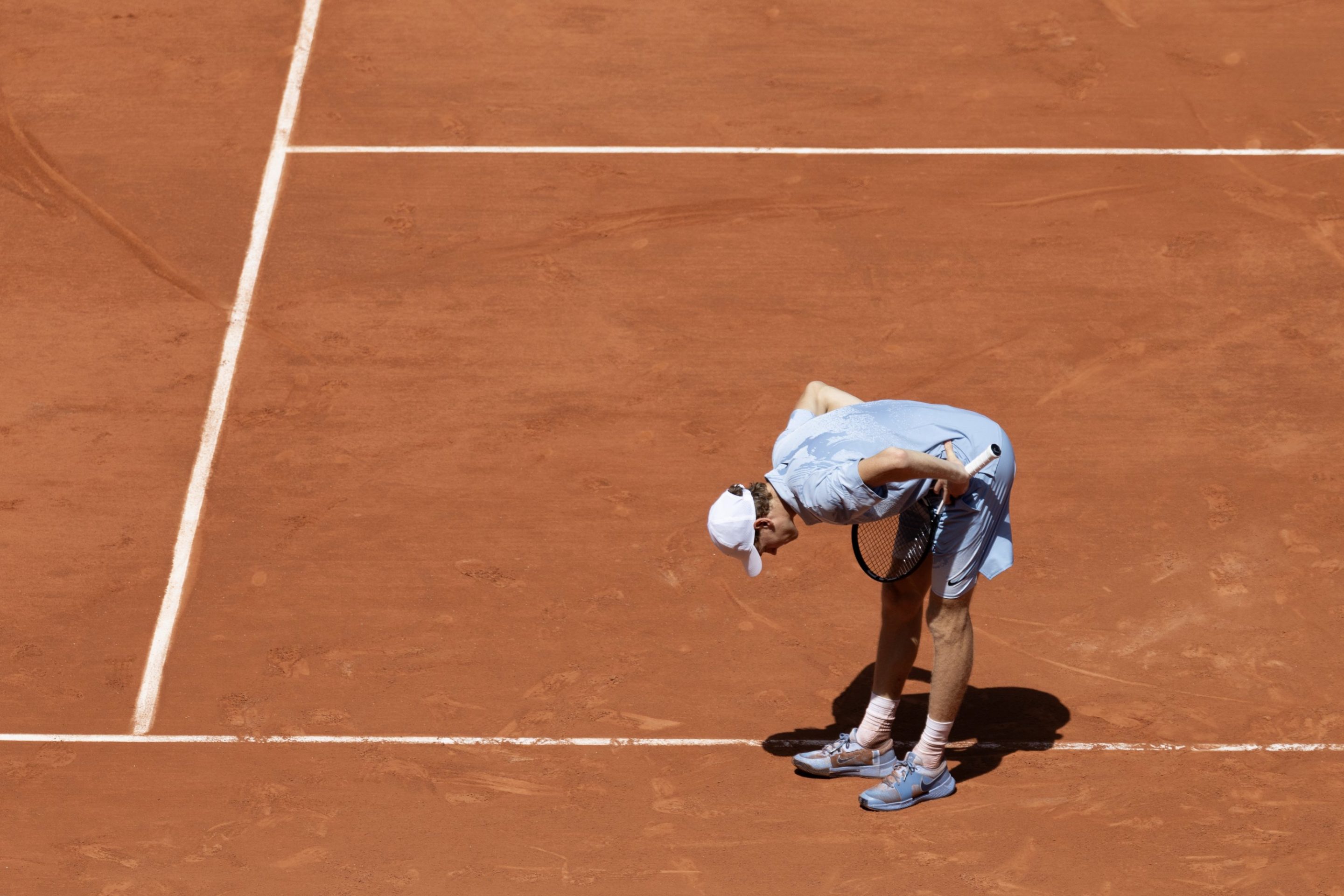 Jannik Sinner bent over in pain during his French Open match