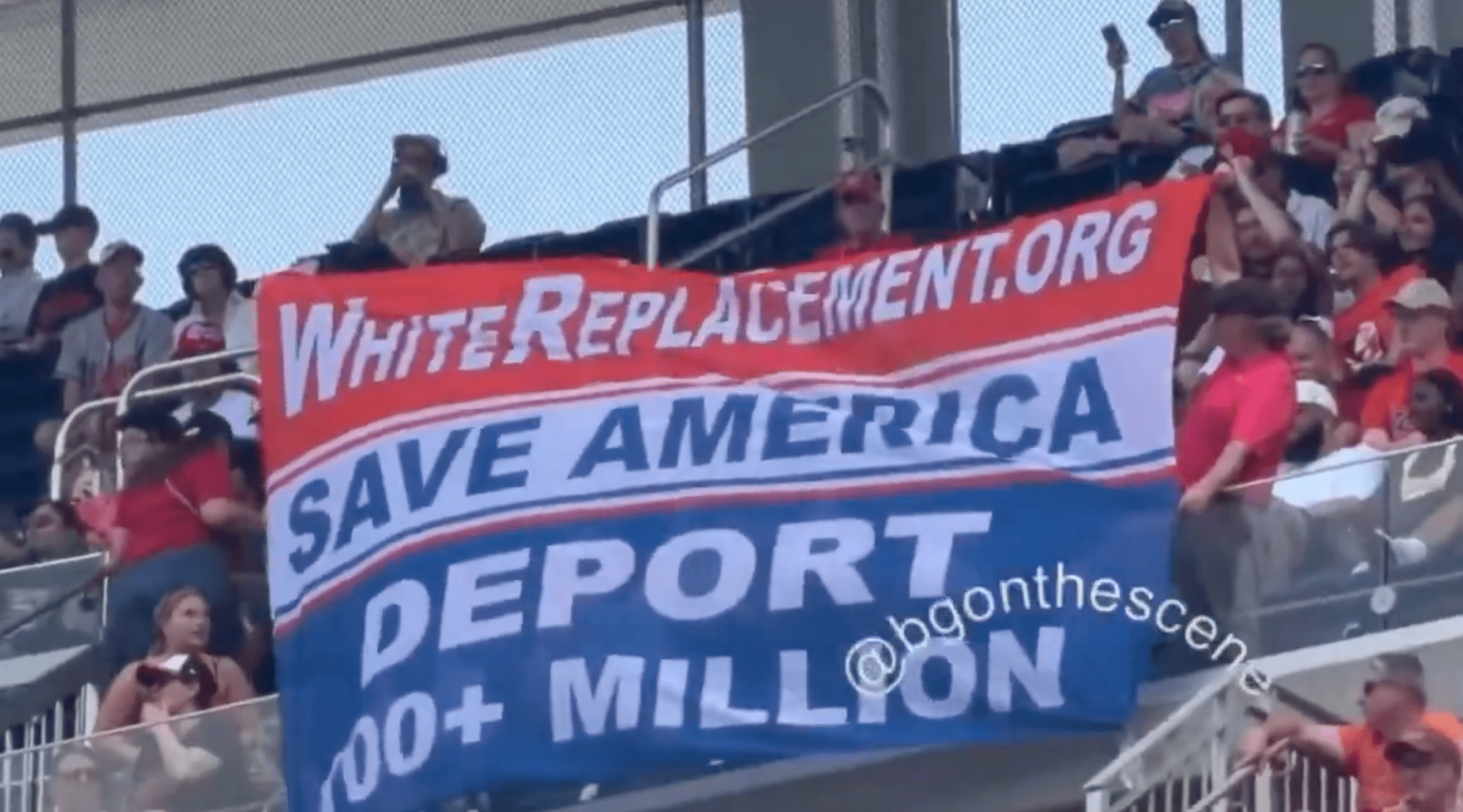Activists unfurl a large banner reading "SAVE AMERICA DEPORT 100+ MILLION" in the stands at Nationals Park