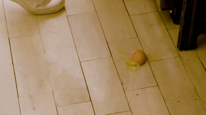An egg broken open on the kitchen floor.