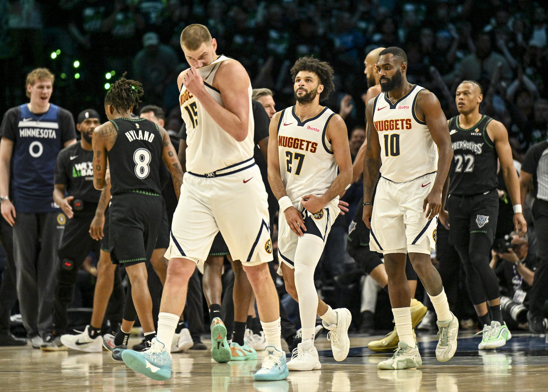 Nikola Jokic (15), Jamal Murray (27) and Tim Hardaway Jr. (10) of the Denver Nuggets walk to the bench for a timeout as the Minnesota Timberwolves celebrate during the third quarter of the Timberwolves' 110-98 Game 6 first round NBA Playoffs series win at the Target Center in Minneapolis, Minnesota on Thursday, April 30, 2026. Minnesota eliminated the Nuggets 4-2. (Photo by AAron Ontiveroz/The Denver Post)
