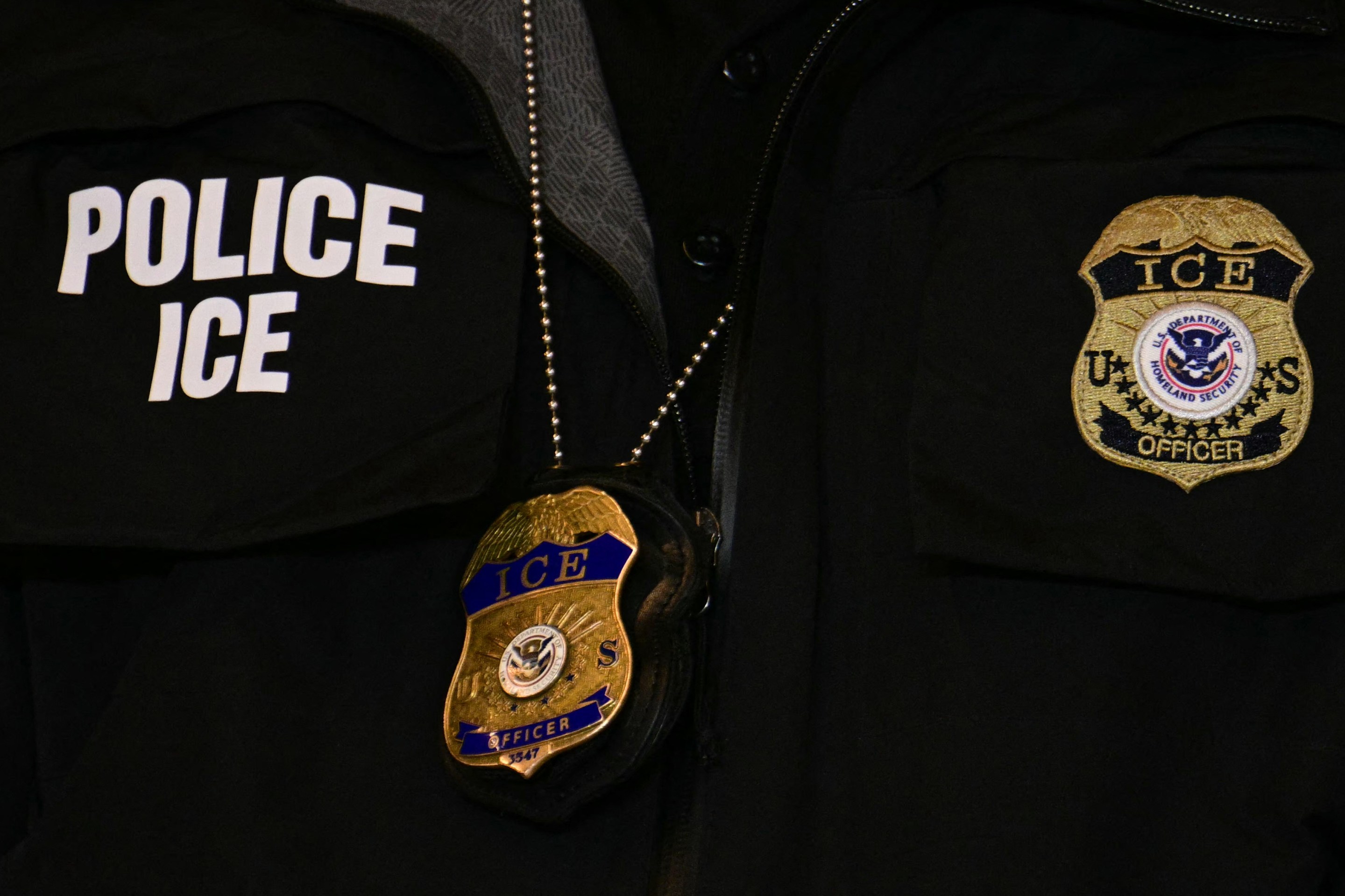 An ICE patch and badge are seen on a Department of Homeland Security agent while US Vice President JD Vance speaks at Royalston Square in Minneapolis, Minnesota, on January 22, 2026. The Pentagon has ordered 1,500 US soldiers to prepare for a possible deployment to Minnesota, a state roiled by unrest over an immigration crackdown, US media reported on January 18, 2026. The reported preparations come days after President Donald Trump threatened to invoke the Insurrection Act, which enables use of the military to suppress "armed rebellion" or "domestic violence" -- although a day later he said there was no immediate need for it, following the January 7 killing of Renee Nicole Good by a federal immigration agent. (Photo by Jim WATSON / POOL / AFP via Getty Images)