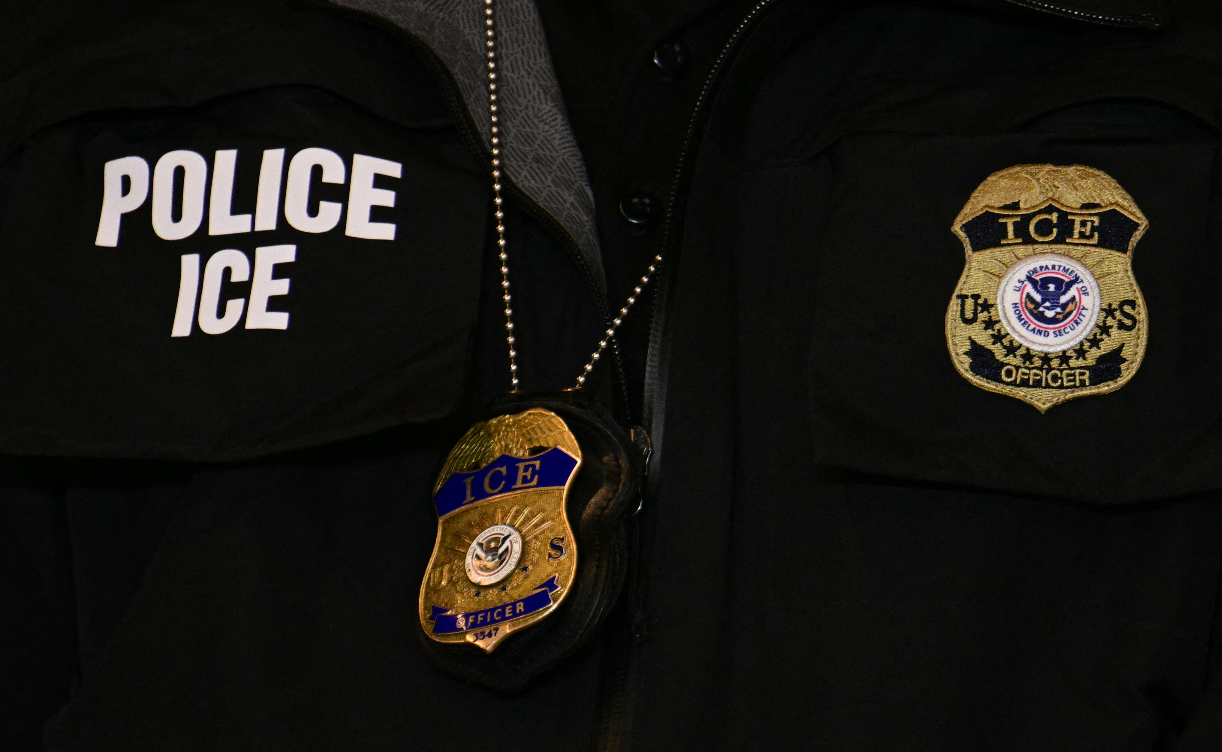 An ICE patch and badge are seen on a Department of Homeland Security agent while US Vice President JD Vance speaks at Royalston Square in Minneapolis, Minnesota, on January 22, 2026. The Pentagon has ordered 1,500 US soldiers to prepare for a possible deployment to Minnesota, a state roiled by unrest over an immigration crackdown, US media reported on January 18, 2026. The reported preparations come days after President Donald Trump threatened to invoke the Insurrection Act, which enables use of the military to suppress "armed rebellion" or "domestic violence" -- although a day later he said there was no immediate need for it, following the January 7 killing of Renee Nicole Good by a federal immigration agent. (Photo by Jim WATSON / POOL / AFP via Getty Images)