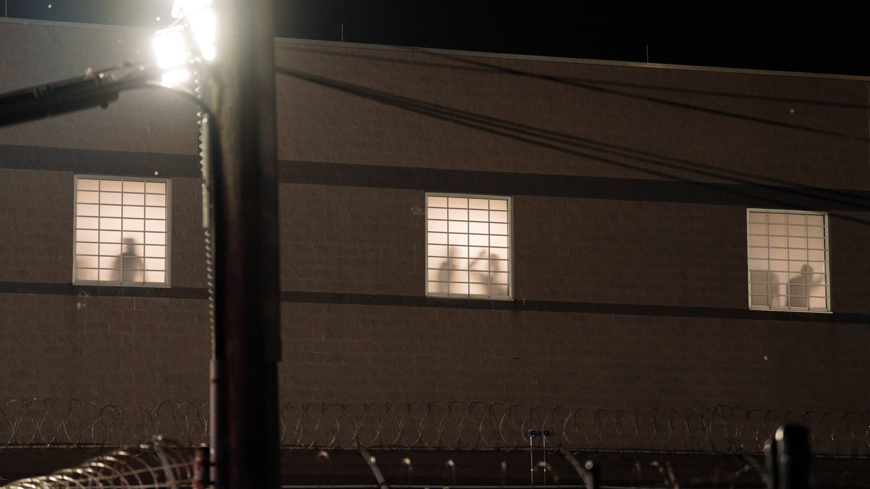 Detainees gesture at windows from inside Delaney Hall Immigration Detention Center