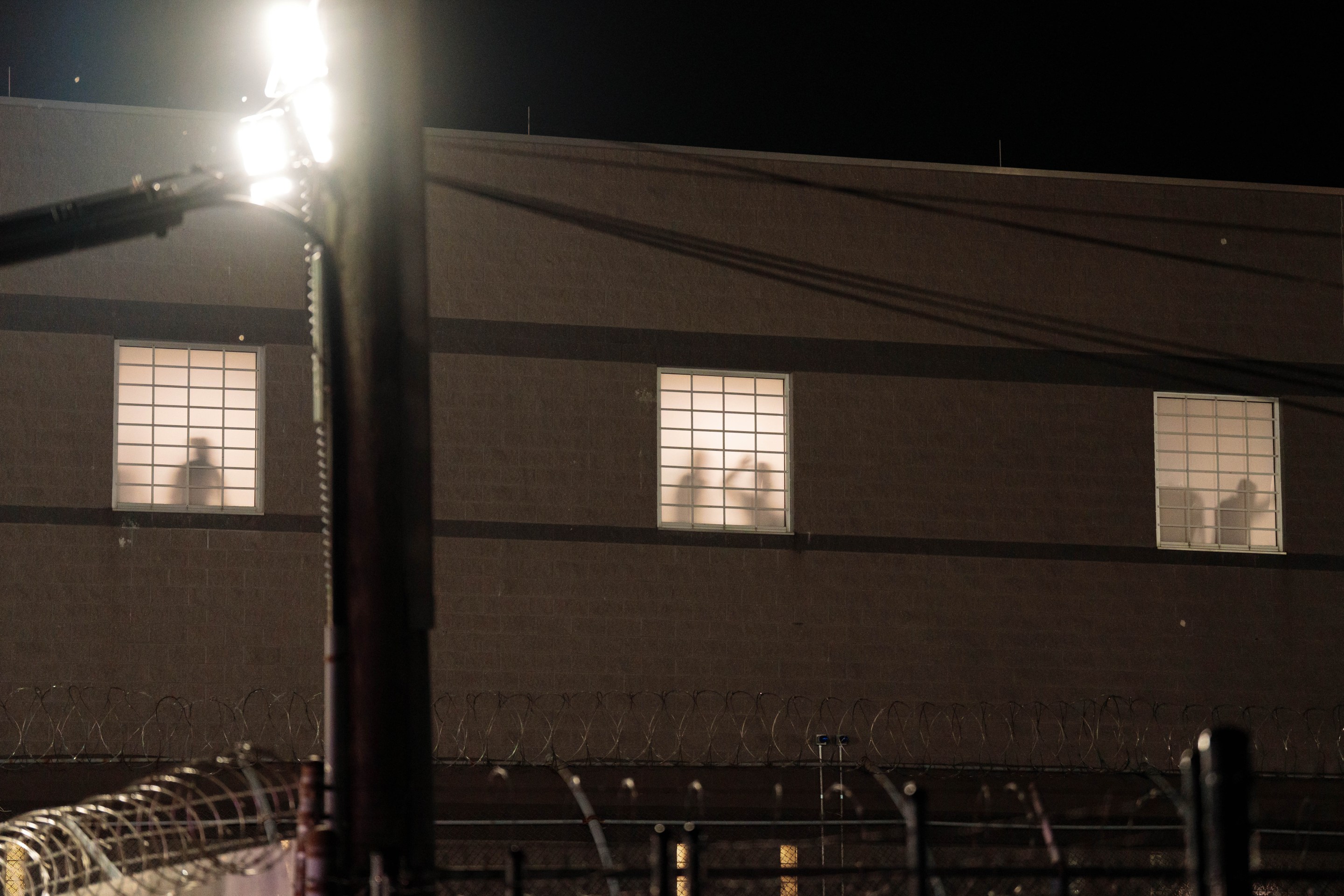 Detainees gesture at windows from inside Delaney Hall Immigration Detention Center