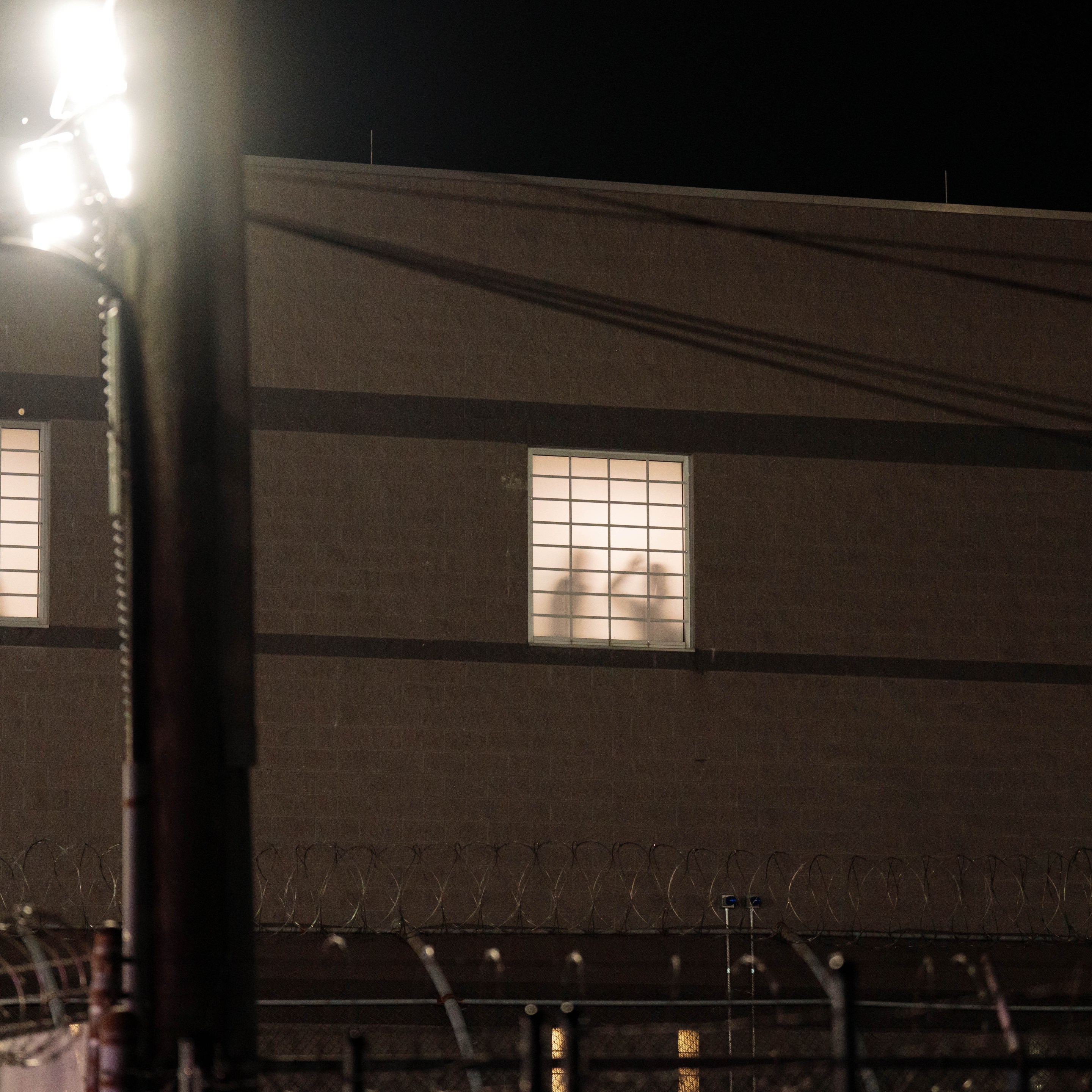 Detainees gesture at windows from inside Delaney Hall Immigration Detention Center