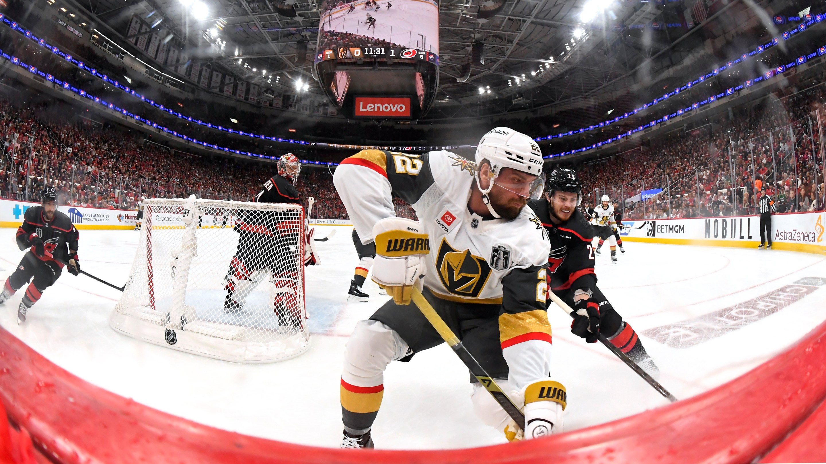 RALEIGH, NORTH CAROLINA - JUNE 02: Alexander Nikishin #21 of the Carolina Hurricanes pressures Cole Smith #22 of the Vegas Golden Knights at the boards during the third period of Game One of the Stanley Cup Final between the Vegas Golden Knights and the Carolina Hurricanes at Lenovo Center on June 02, 2026 in Raleigh, North Carolina. (Photo by Brian Babineau/NHLI via Getty Images)