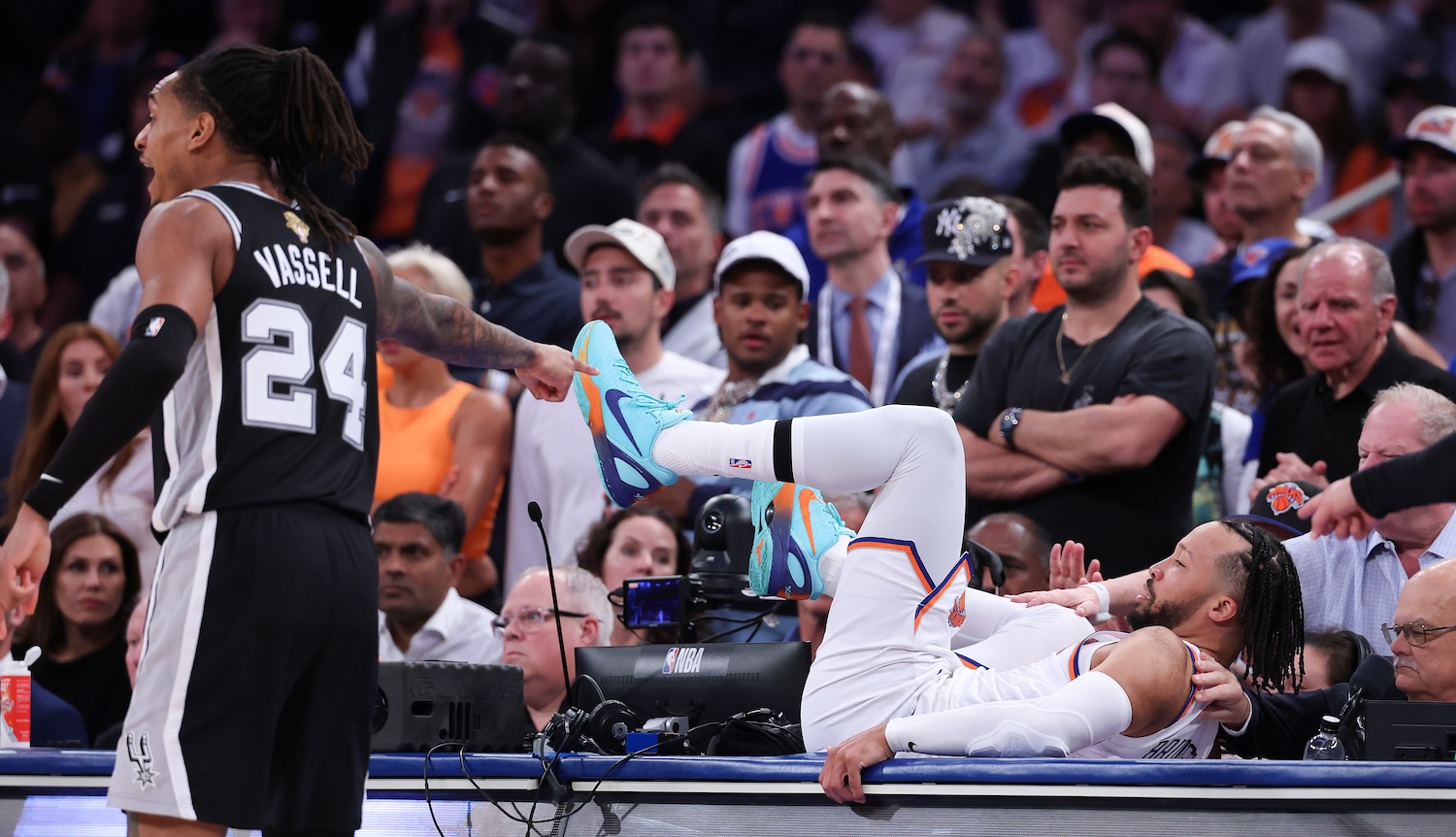 NEW YORK, NEW YORK - JUNE 08: Jalen Brunson #11 of the New York Knicks lands on the scorers table as Devin Vassell #24 of the San Antonio Spurs reacts during the fourth quarter in Game Three of the 2026 NBA Finals at Madison Square Garden on June 08, 2026 in New York City. NOTE TO USER: User expressly acknowledges and agrees that, by downloading and or using this photograph, User is consenting to the terms and conditions of the Getty Images License Agreement. (Photo by Al Bello/Getty Images)