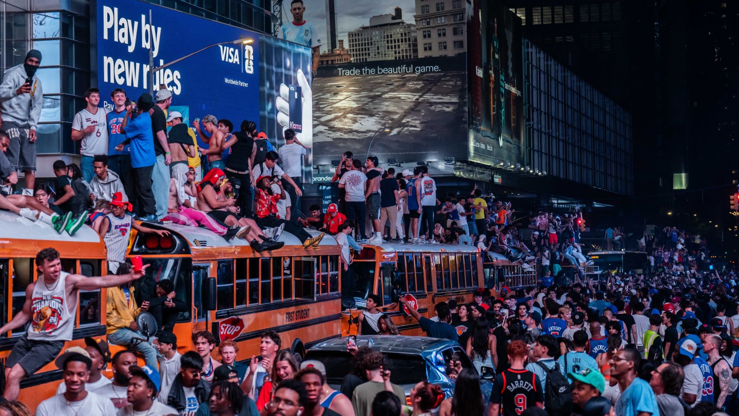 NEW YORK, NEW YORK - JUNE 14: New York Knicks fans climb on buses as they celebrate after they win the NBA Finals in Times Square on June 14, 2026 in New York City. The New York Knicks lead the San Antonio Spurs 3-1 and could win the franchise's first NBA championship since 1973 if they win tonight.(Photo by Adam Gray/Getty Images)