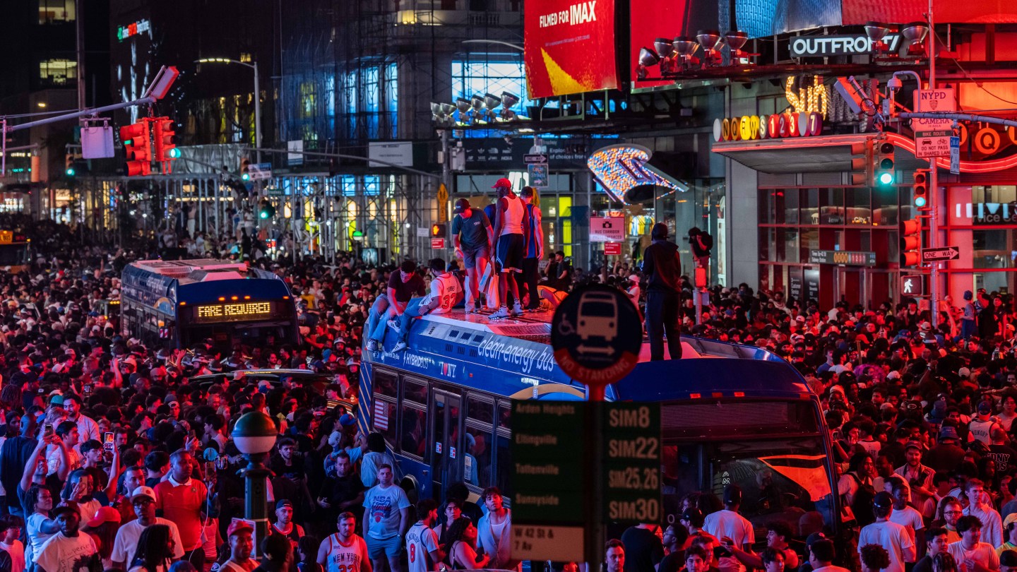 NEW YORK, NEW YORK - JUNE 14: New York Knicks fans climb on buses as they celebrate after they win the NBA Finals in Times Square on June 14, 2026 in New York City. The New York Knicks lead the San Antonio Spurs 3-1 and could win the franchise's first NBA championship since 1973 if they win tonight.(Photo by Adam Gray/Getty Images)