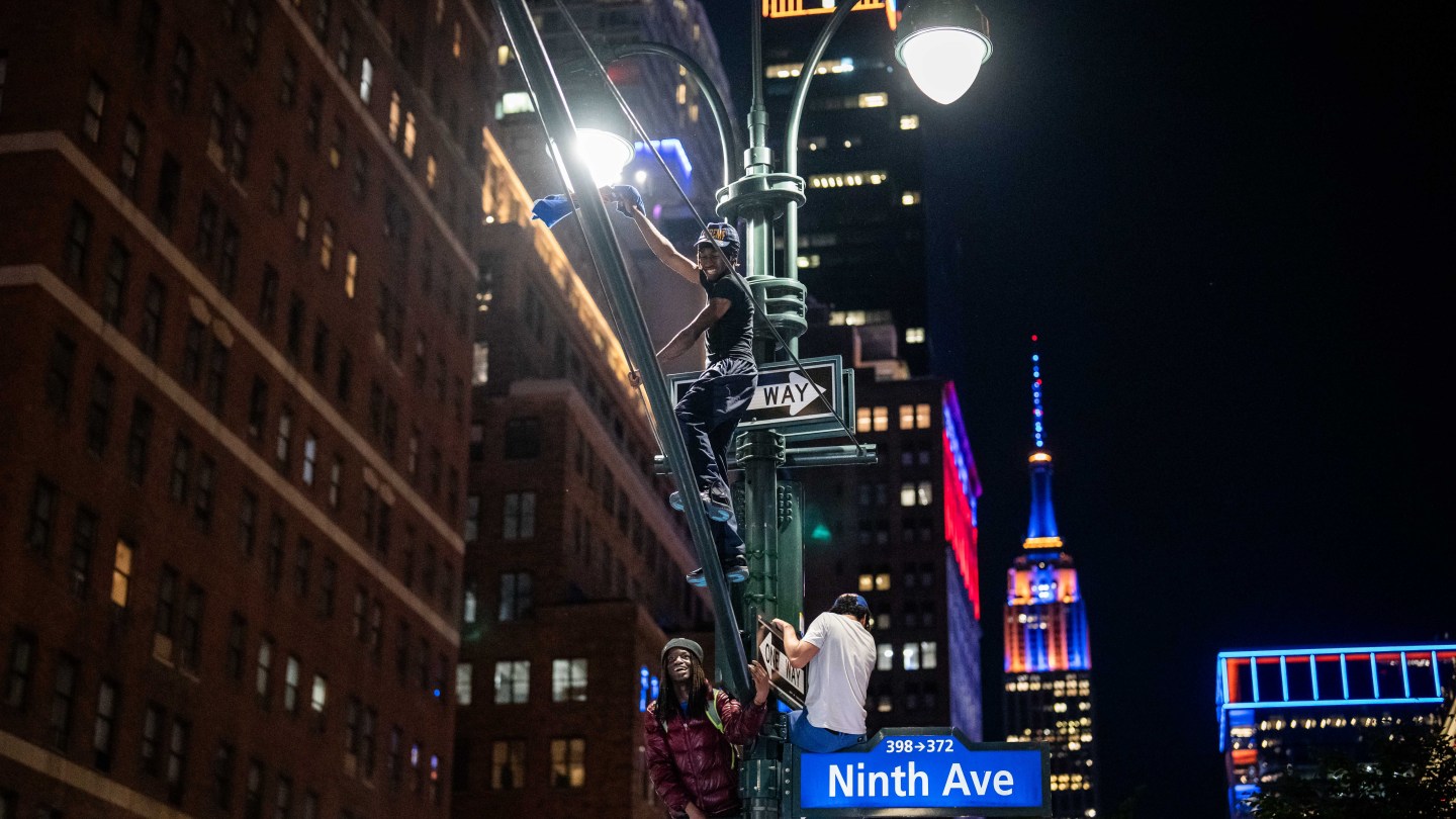 NEW YORK, NEW YORK - JUNE 13: New York Knicks fans climb lamp posts as they celebrate their win against San Antonio Spurs in Game 5 of the NBA Finals on June 13, 2026 in New York City. The New York Knicks lead the San Antonio Spurs 3-1 and could win the franchise's first NBA championship since 1973 if they win tonight.(Photo by Adam Gray/Getty Images)