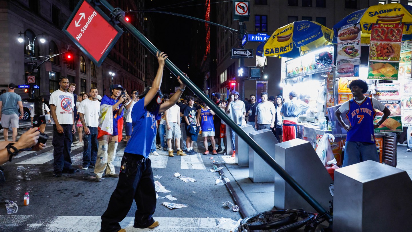Knicks fans remove a street sign as they celebreated in midtown after the New York Knicks defeated the San Antonio Spurs in Game 5 of the NBA Finals to win the series, in New York, on June 14, 2026. The Knicks won the NBA Championship for the first time since 1973, for the third time in franchise history. (Photo by kena betancur / AFP via Getty Images)
