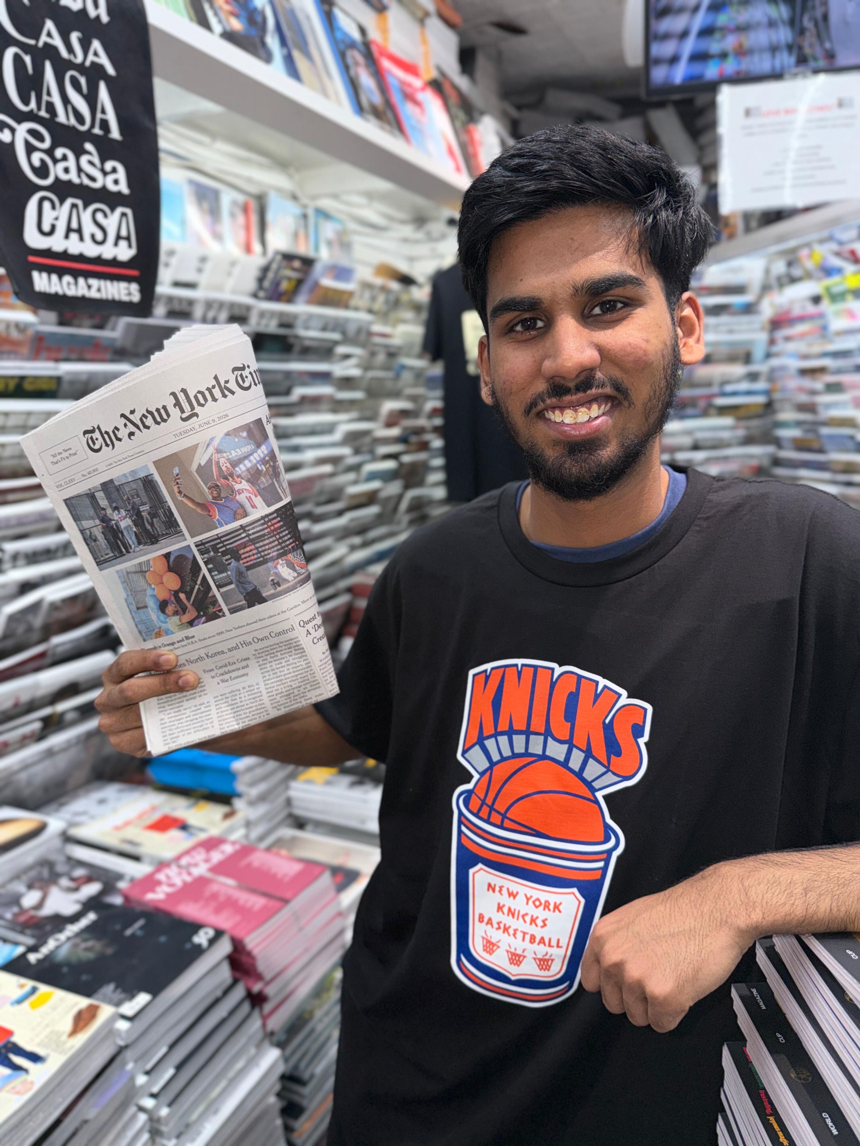 Casa Magazines staffer Mirza Ayan Baig holds up a recent Knicks front page.