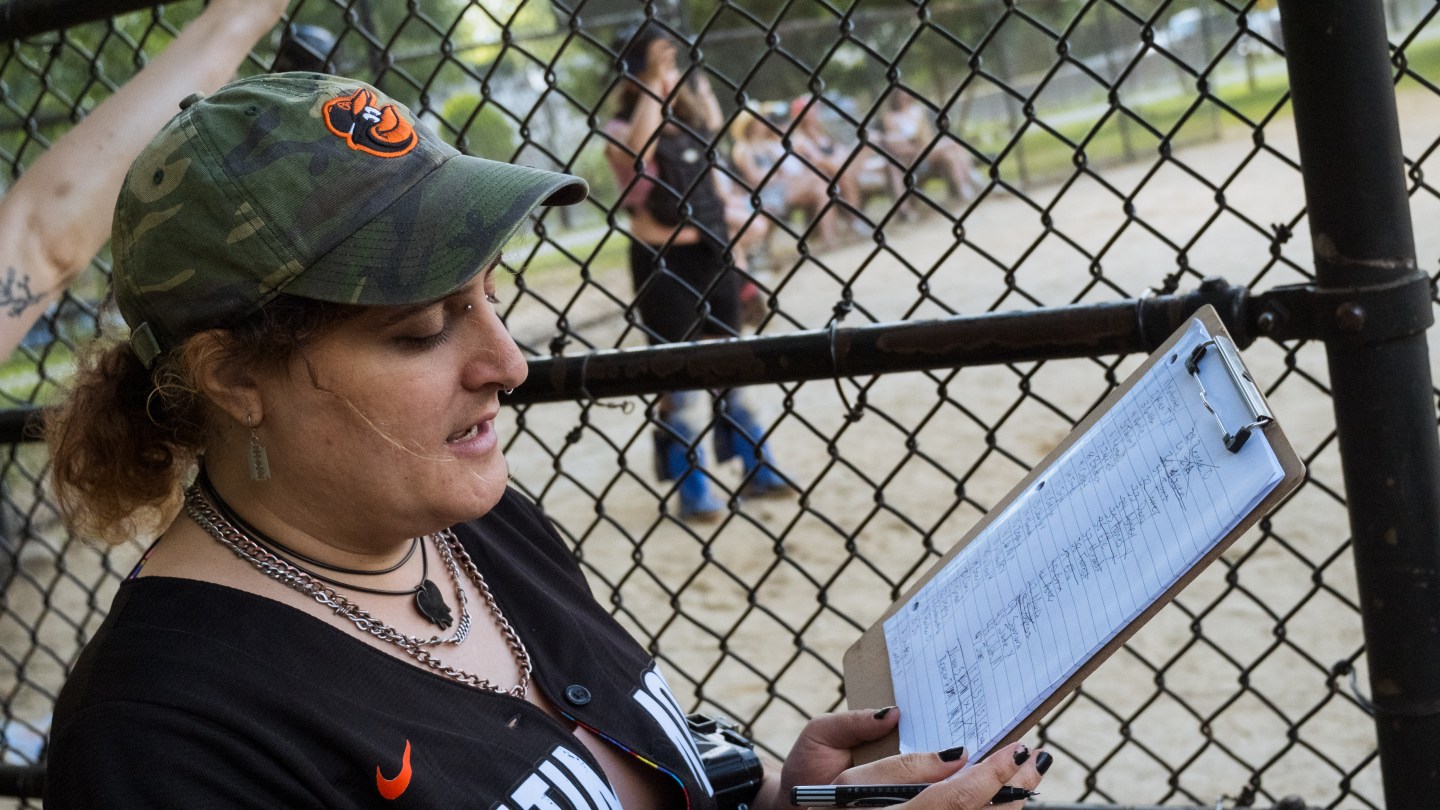 a woman looks at a lineup card in the bench area