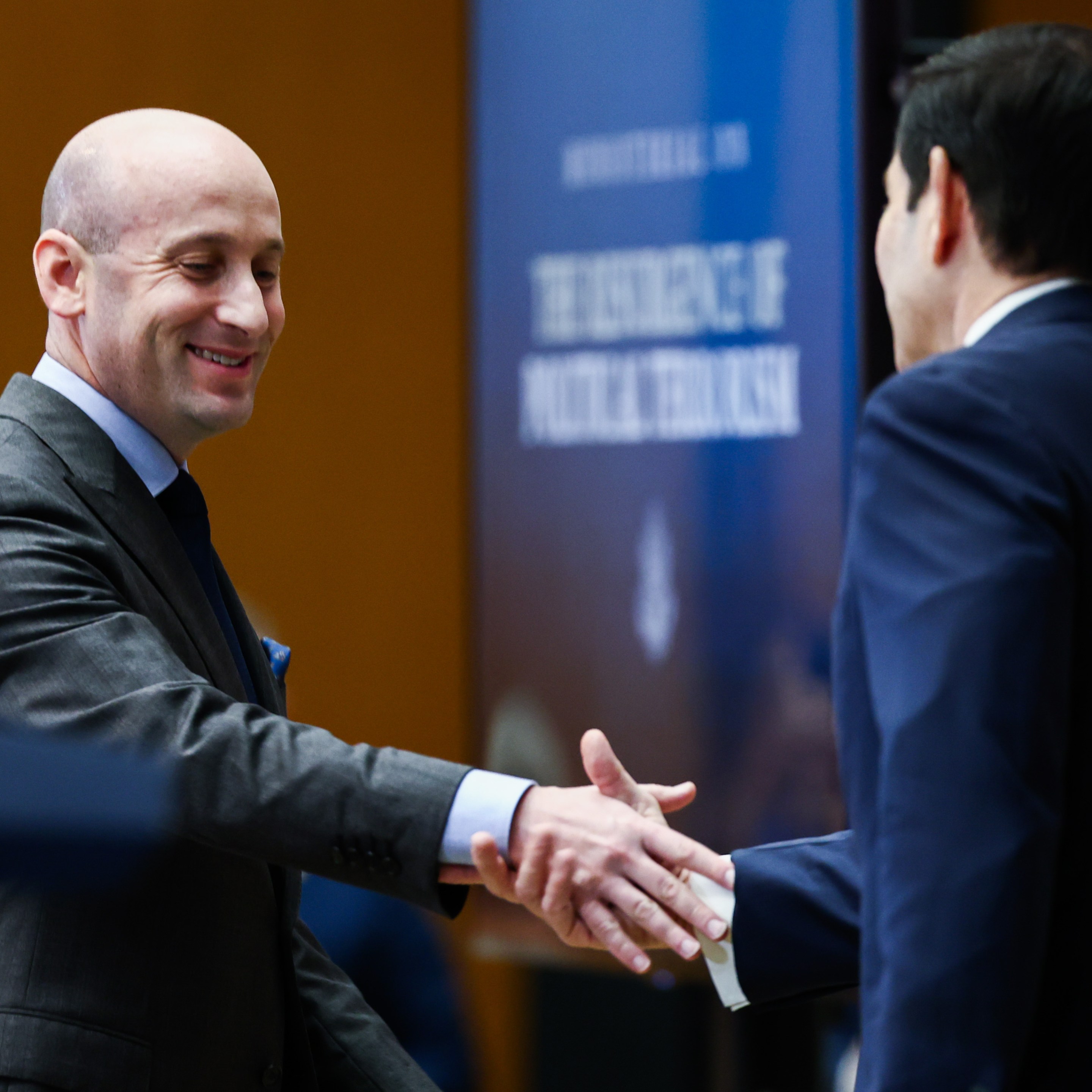 White House Deputy Chief of Staff Stephen Miller (L) shakes hands with U.S. Secretary of State Marco Rubio before addressing the audience