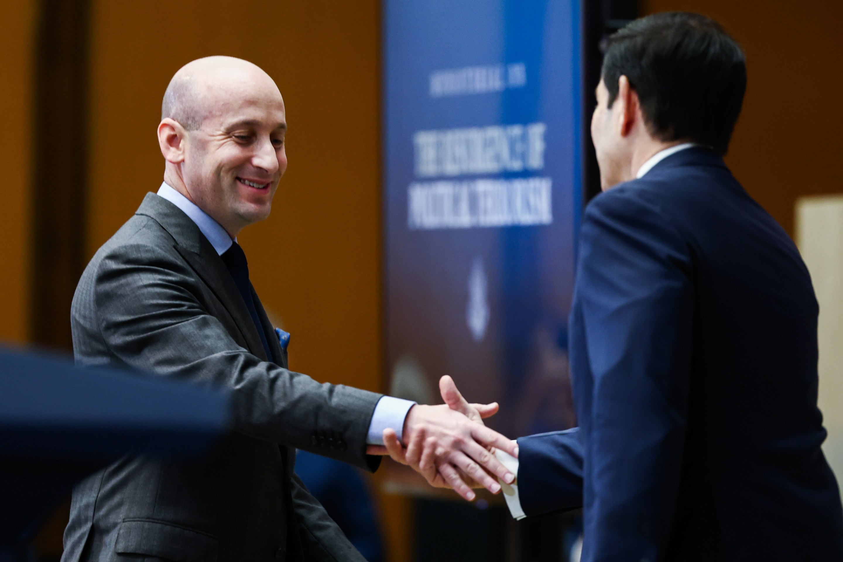 White House Deputy Chief of Staff Stephen Miller (L) shakes hands with U.S. Secretary of State Marco Rubio before addressing the audience