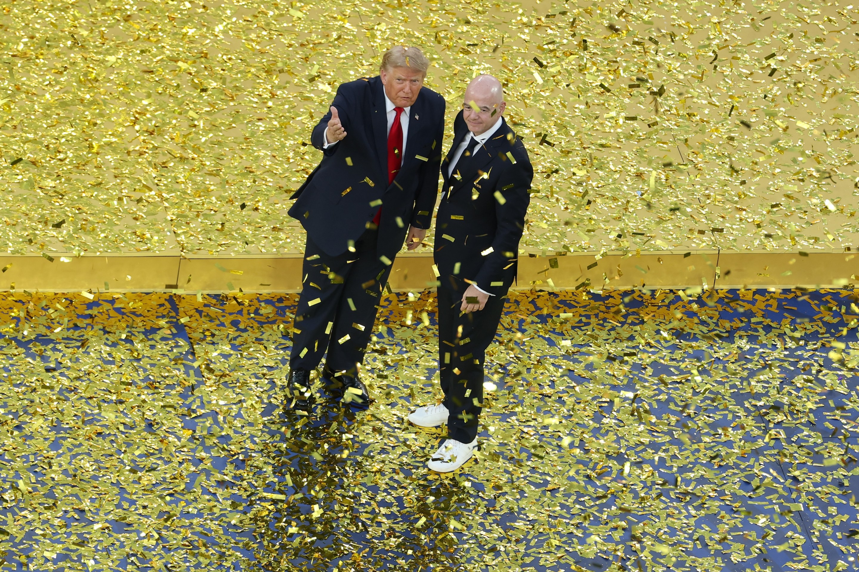U.S. President Donald Trump reacts next to FIFA President Gianni Infantino after presenting the FIFA World Cup Winner's Trophy to Spain in the World Cup Final. Trump's kind of leaning like there's a very heavy wind.