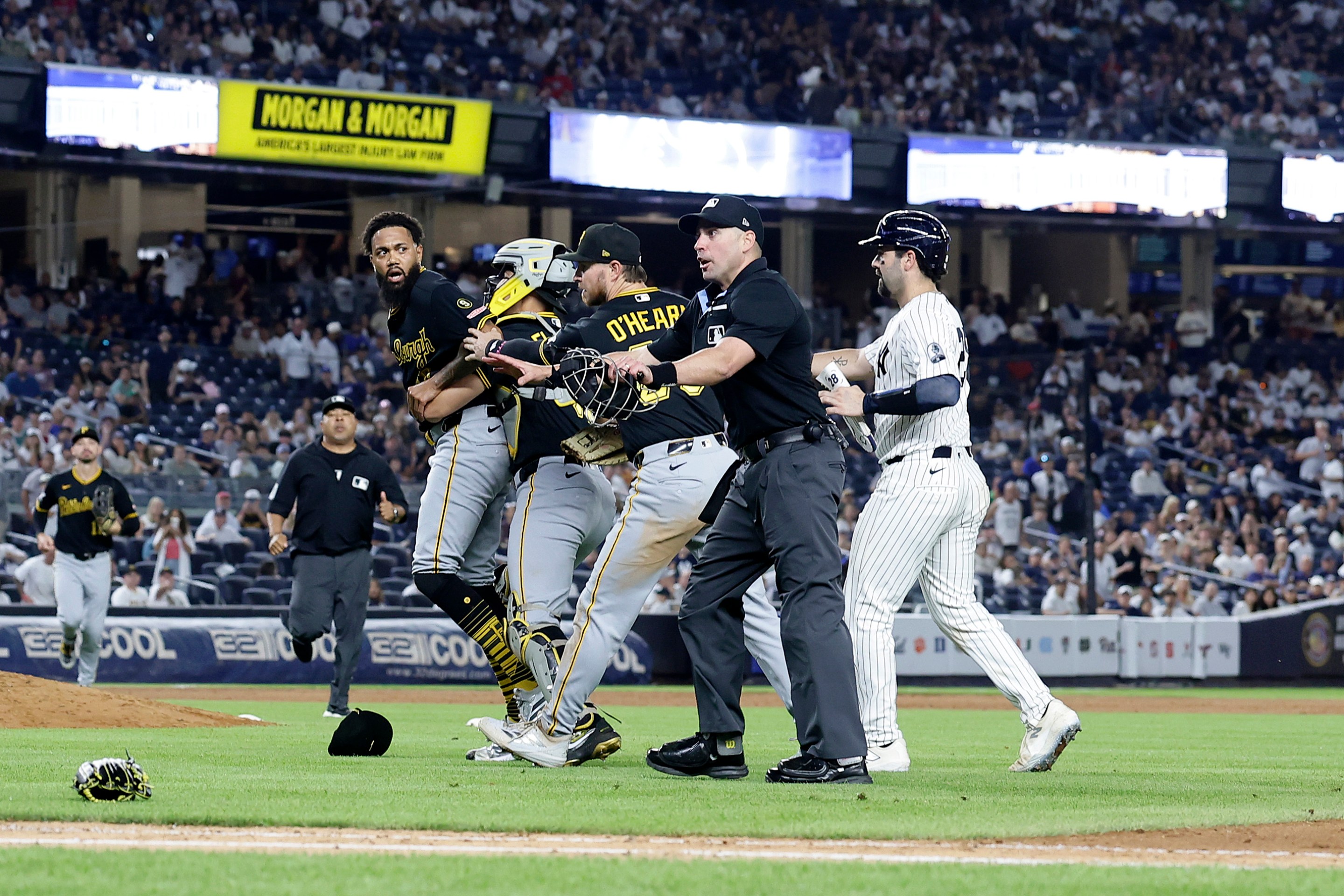 Dennis Santana #60 of the Pittsburgh Pirates is restrained by teammates Rafael Flores Jr. #43 and Ryan O'Hearn #29 of the Pittsburgh Pirates as Austin Wells #28 of the New York Yankees moves in during an altercation after the eighth inning at Yankee Stadium