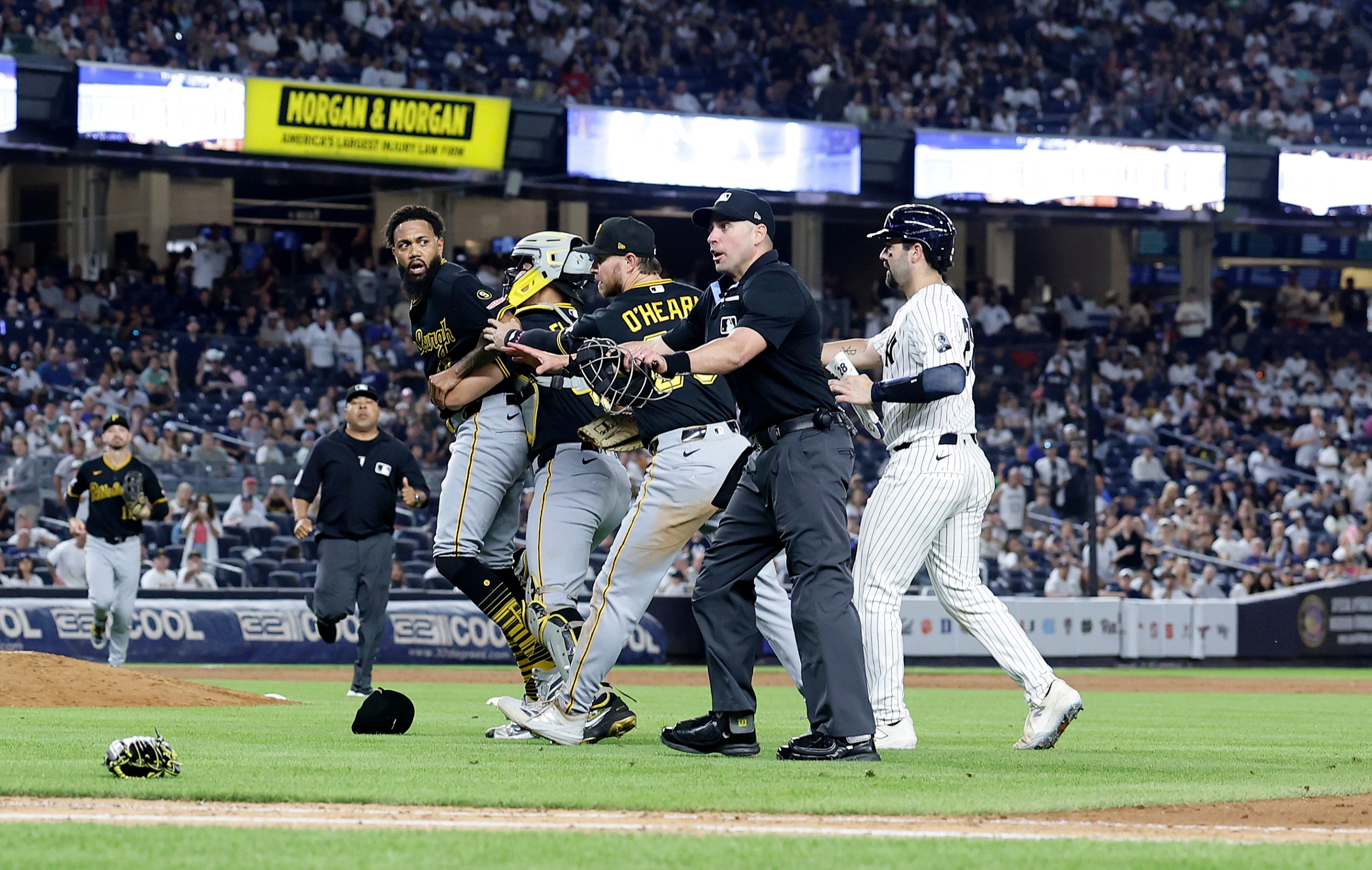 Dennis Santana #60 of the Pittsburgh Pirates is restrained by teammates Rafael Flores Jr. #43 and Ryan O'Hearn #29 of the Pittsburgh Pirates as Austin Wells #28 of the New York Yankees moves in during an altercation after the eighth inning at Yankee Stadium