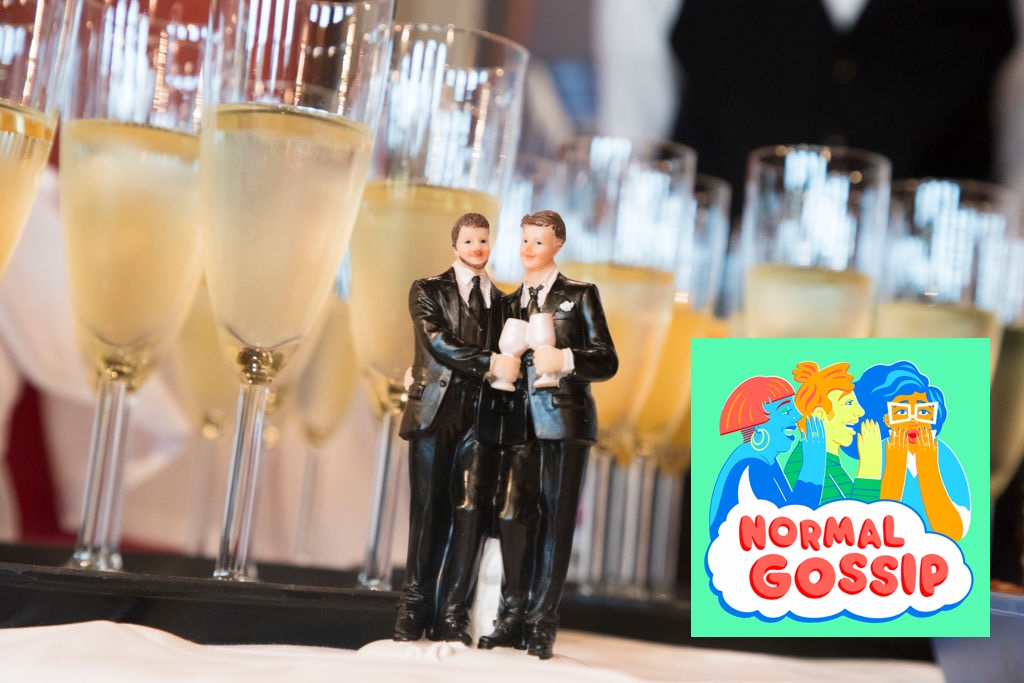 The photo shows filled champagne glasses and and the top to a wedding cake of two grooms in tuxedos holding wine glasses.