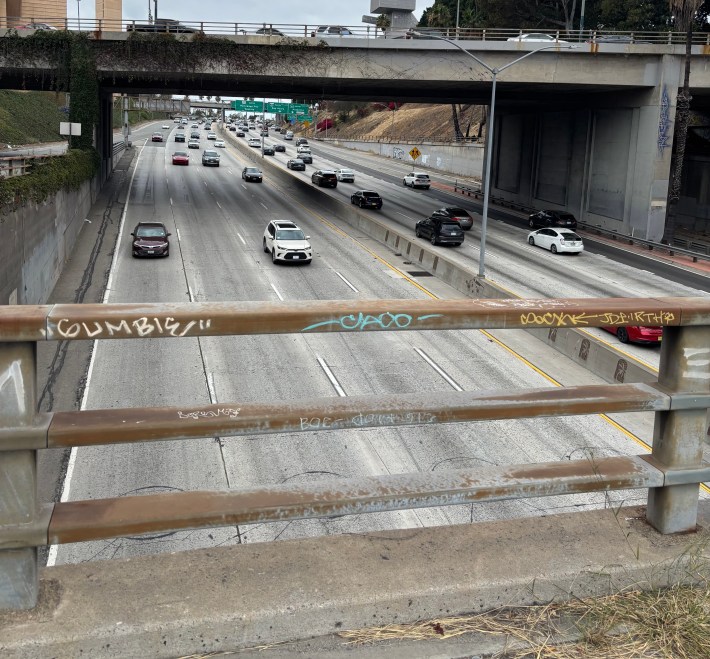 A photo of a highway set behind a metal railing.