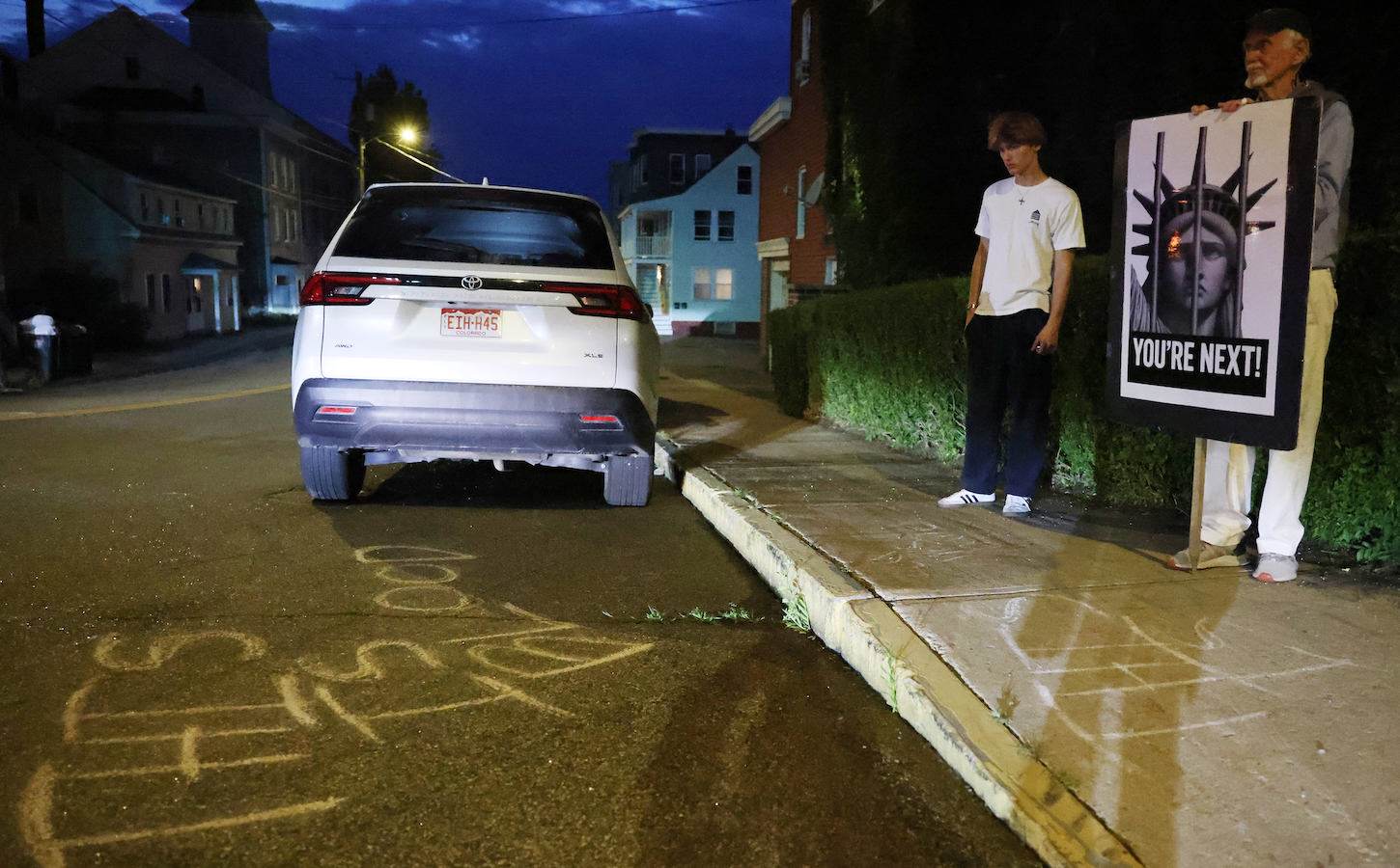 People stand at the scene of an ICE shooting that killed a man on July 13, 2026.