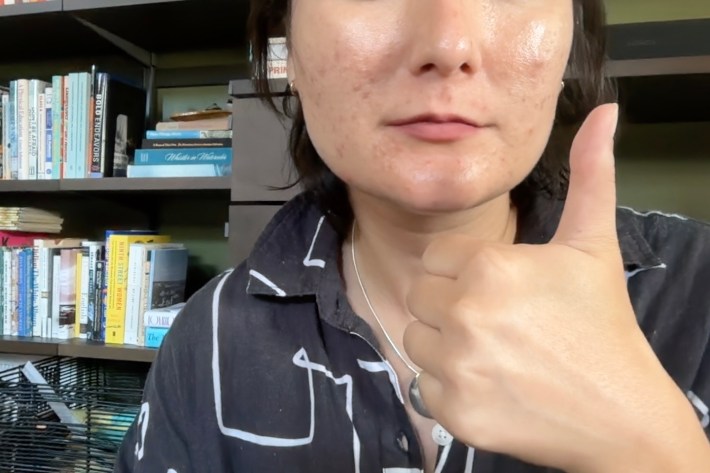 Alex shows off final product of lining lips. She gives a thumbs up to show the process is going well.