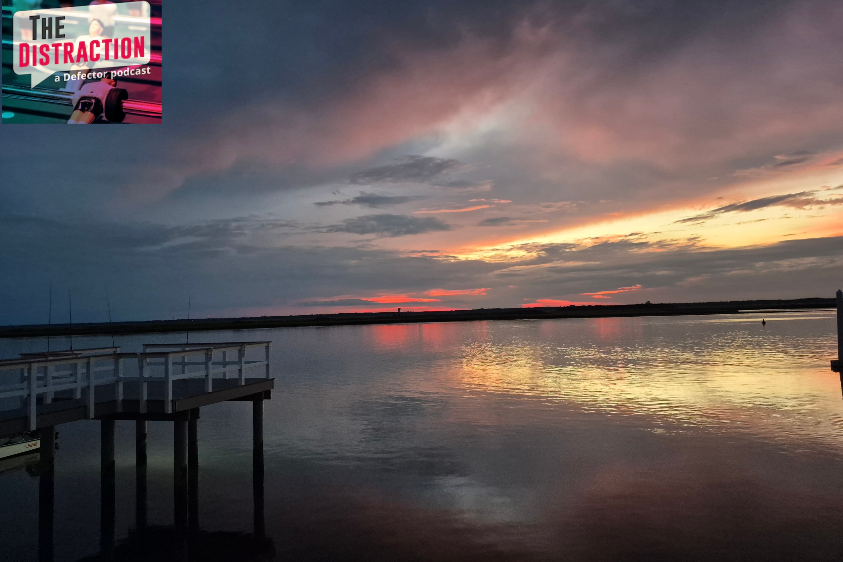 A photo I took of the sun setting over the bay in Strathmere, NJ. There's a dock at left and The Distraction logo at upper left.