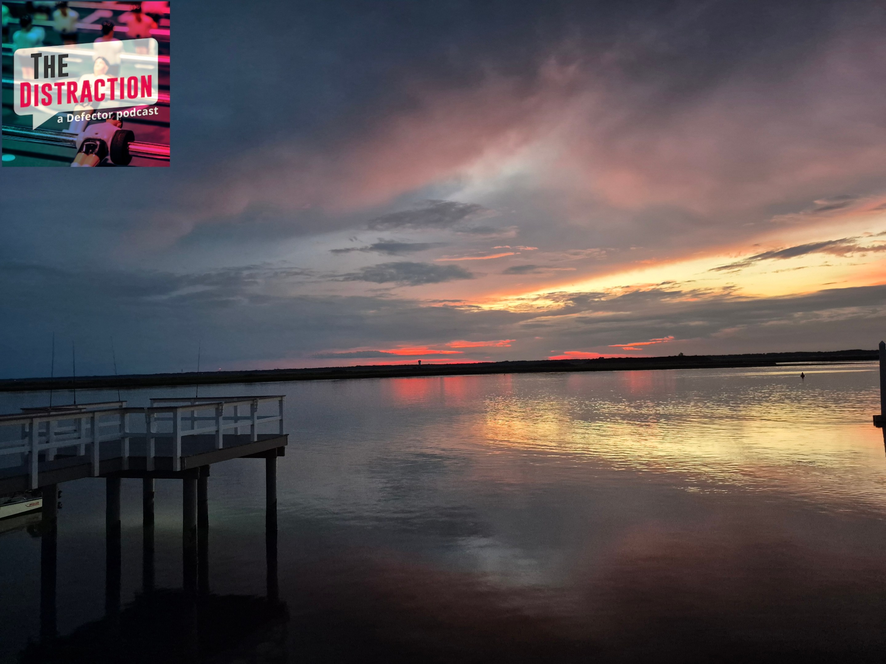 A photo I took of the sun setting over the bay in Strathmere, NJ. There's a dock at left and The Distraction logo at upper left.