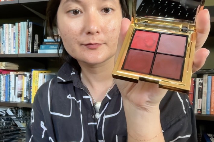 Alex holds up the lipstick palette she's using for the blog. It's a small gold case with four different reddish pigments in it.