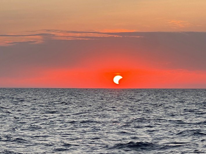 A partial solar eclipse at sunset over the Mediterranean.