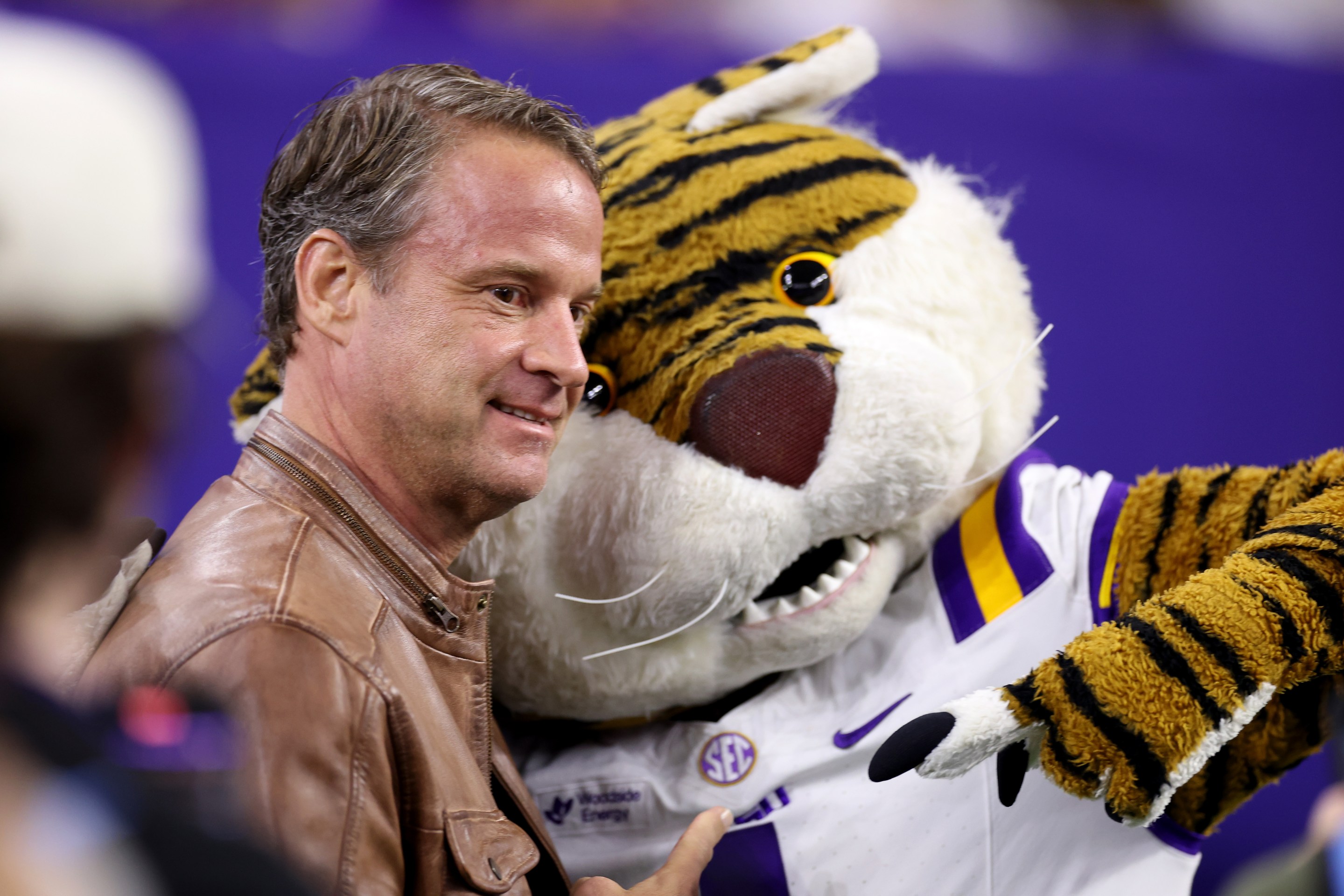 HOUSTON, TEXAS - DECEMBER 27: Head coach Lane Kiffin of the Louisiana State Tigers poses with the mascot before the game against the Houston Cougars during the Kinder's Texas Bowl at NRG Stadium on December 27, 2025 in Houston, Texas.