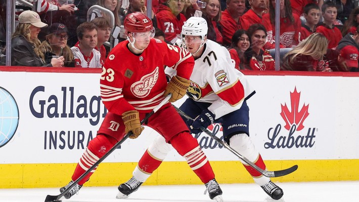 Lucas Raymond #23 of the Detroit Red Wings tries to keep the puck from Niko Mikkola #77 of the Florida Panthers during the third period of a game at Little Caesars Arena on March 06, 2026 in Detroit, Michigan.