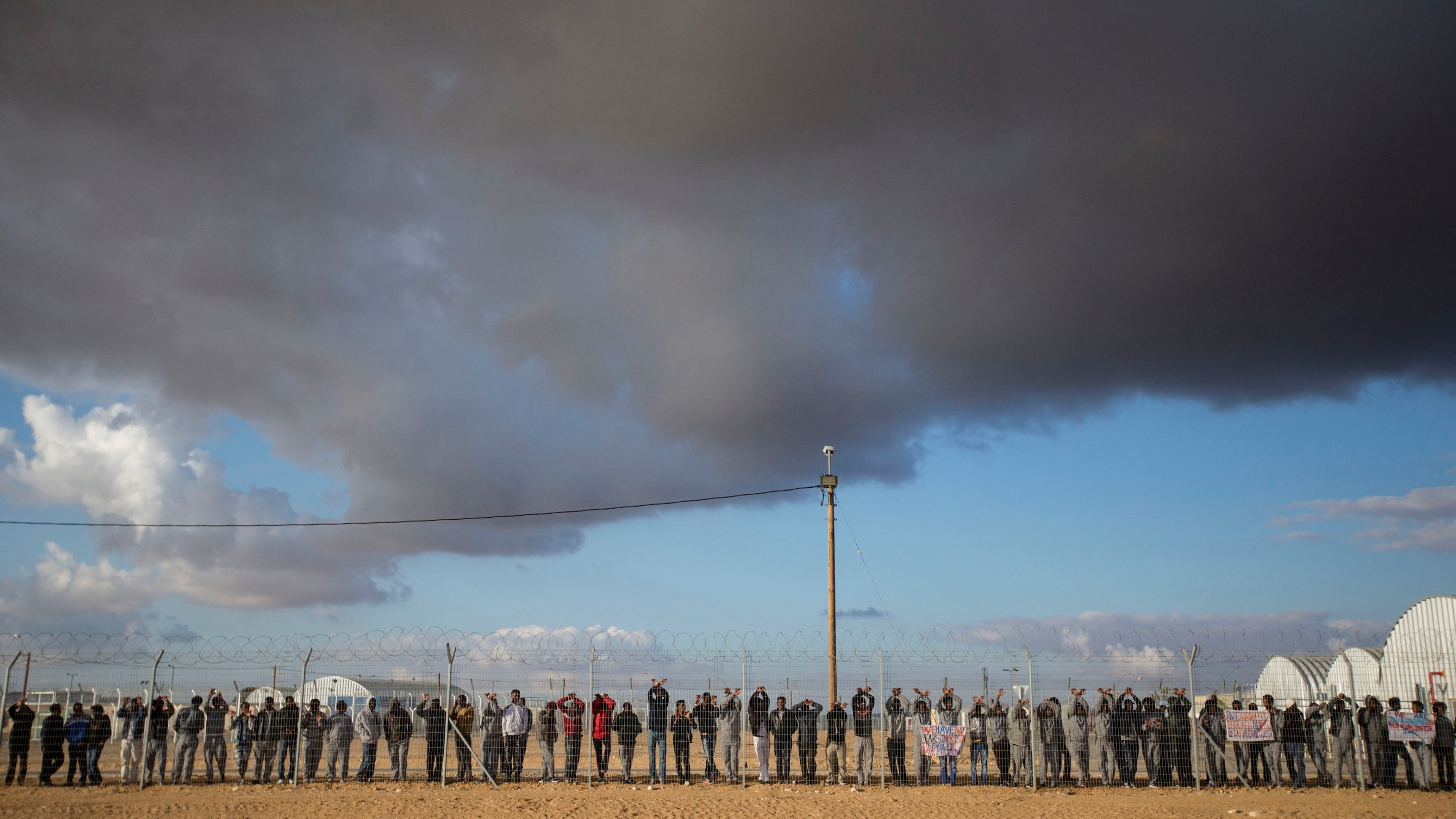 Asylum seekers, who entered Israel illegally via Egypt, lean at the fence of the Holot detention centre in Israel's southern Negev Desert, on February 17, 2014.