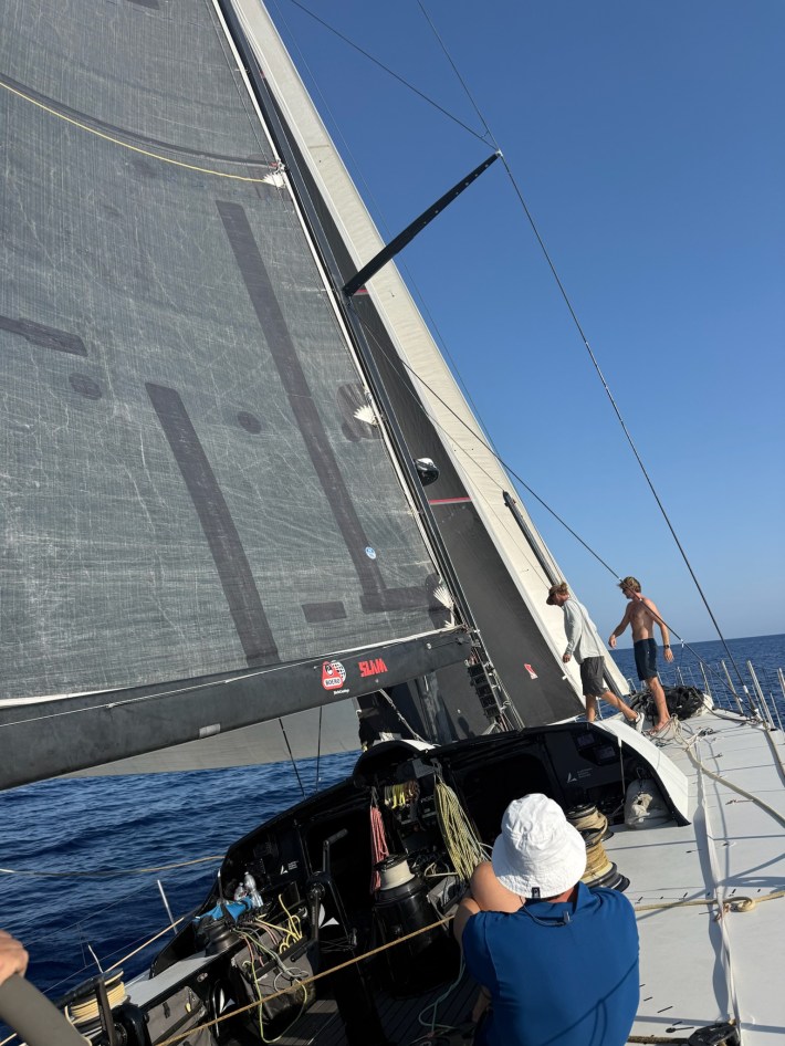 The view forward from near the starboard helm, as Sisi heels to port. Some members of Sisi's crew are up on the bow, evaluating her sail trim.