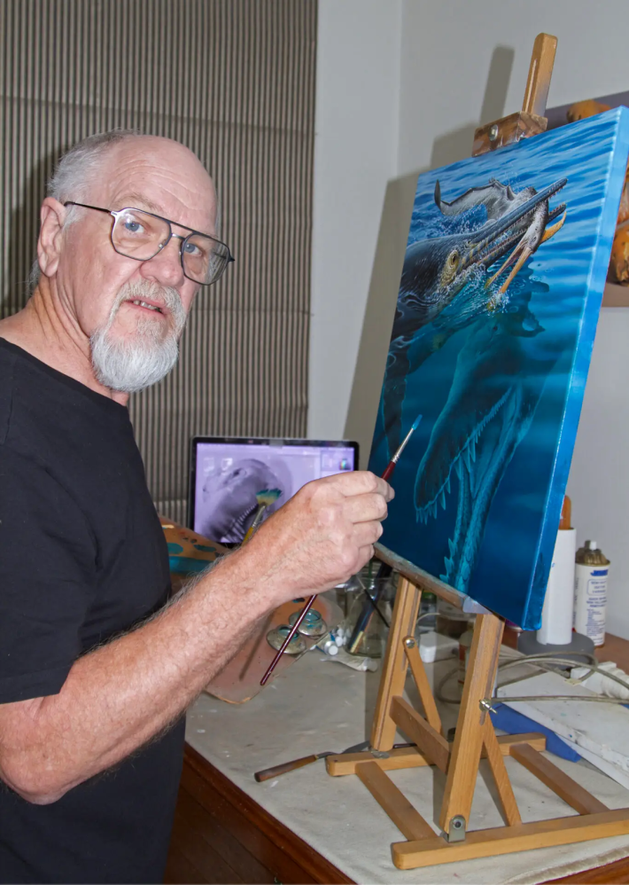 Peter Trusler painting the pliosaur lurking below the ichthyosaur eating the pterosaur
