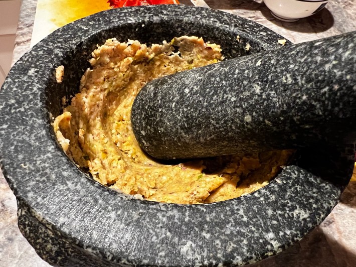Smashed garlic, bread, and nuts in a heavy mortar.