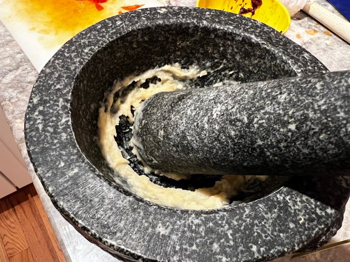 Smashed garlic in a heavy mortar.