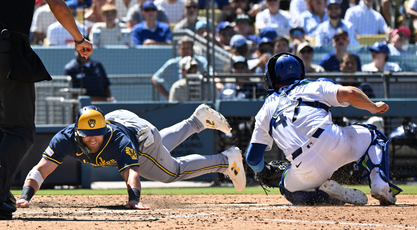 Jake Bauers of the Milwaukee Brewers diving past Los Angeles Dodgers catcher Ben Rortvedt on a play at home plate.