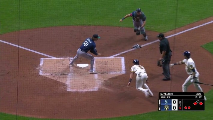 Cal Raleigh approaches home plate from the first base line while Jake Bauers runs back to home plate, while Bryce Miller attempts to cover home.