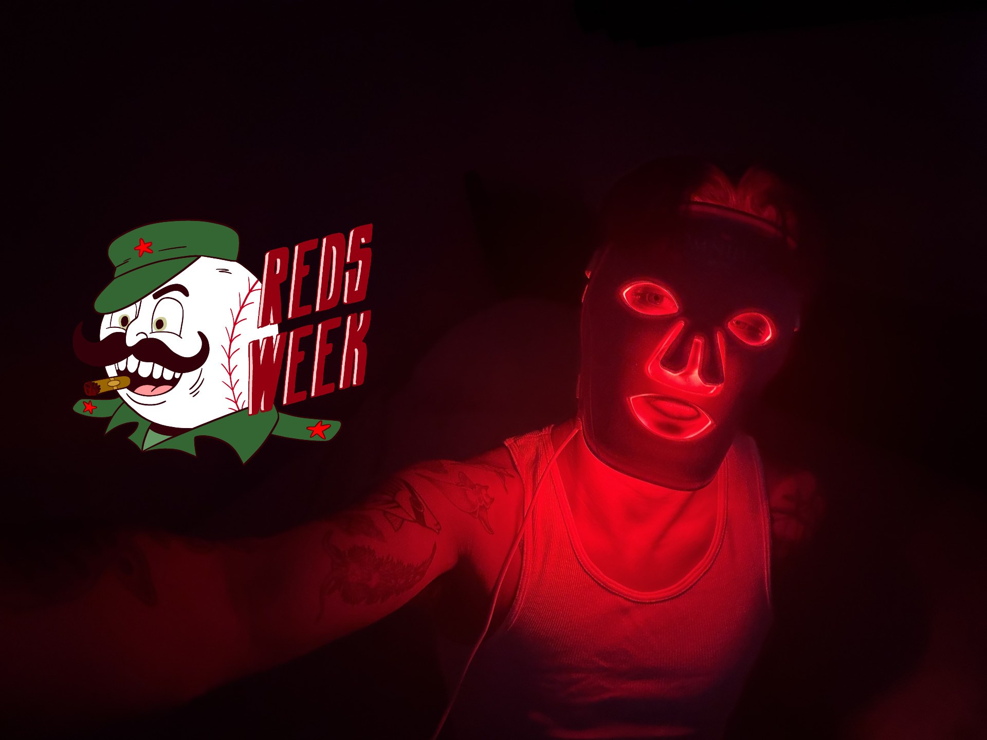 a photo of a person in a red light mask in a dark room, with the reds week logo next to it